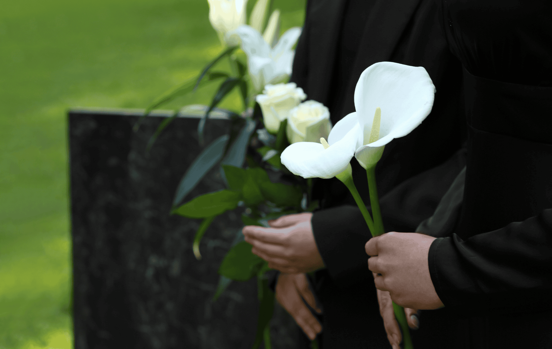 Personnes tenant des fleurs blanches sur un lieu de cérémonie funéraire.